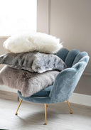 Grey faux fur decorative pillow styled on a bed as a luxurious bedroom accent