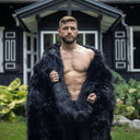 The image shows a man relaxing under an ultra-soft black throw made from high-quality long-pile faux fur. The deep, elegant black and plush texture add character and sophistication to any interior. Perfect for modern spaces that value both comfort and luxurious design.